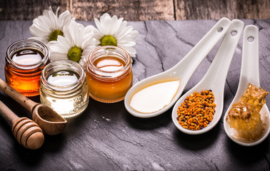 Honey in jar with honey dipper on black stone background