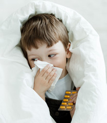 boy wipes his nose with a tissue