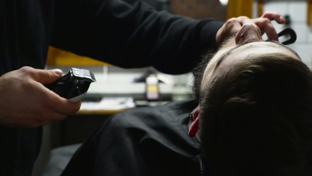 Barber shaves the beard of the client with clipper slow motion