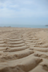 Fototapeta na wymiar Close up on tyre traces on dry sand background
