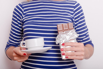 Hands holding chocolate and cup of drink on white background