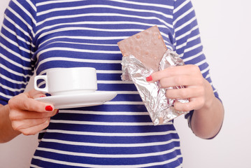 Hands holding chocolate and cup of drink on white background
