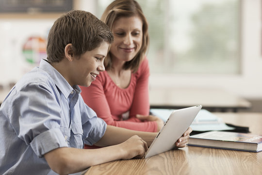 Two children, a boy and girl sitting sharing a digital tablet. 