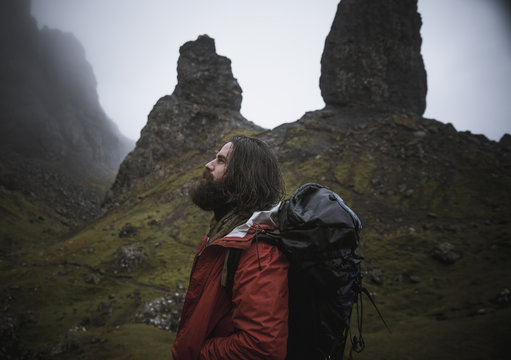 Man with backpack standing in mountain landscape, Isle of Skye, Scotland