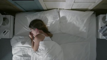 Young woman can't sleep, tossing and turning in bed at night. High angle view