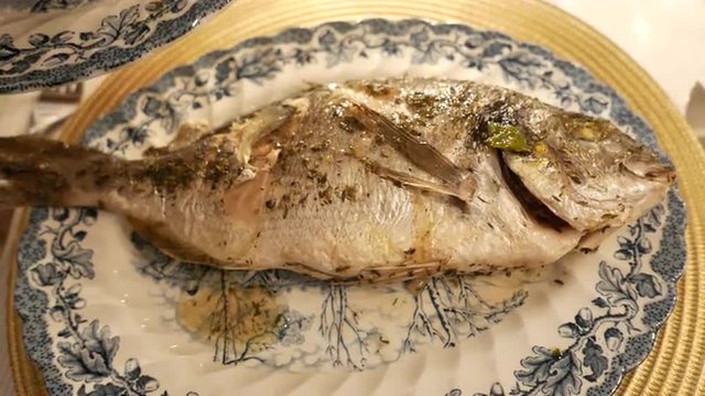 Adding oil and sauce to freshly grilled fish Elegant plates and setting