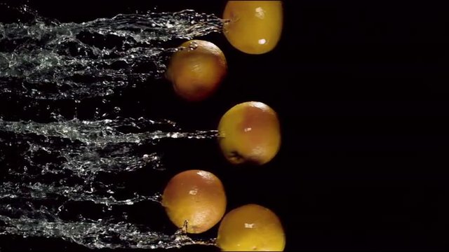grapefruits are flying with a jet of water on a black  background, slow motion
