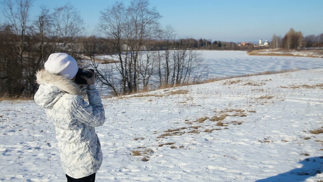Girl with the camera photographs the landscape in winter day.young girls photographing outdoors.