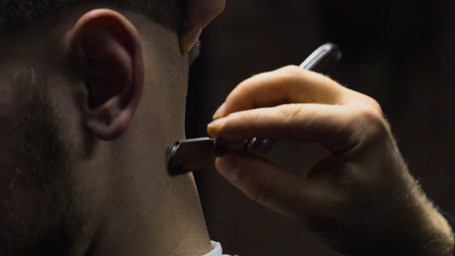 Barber shaves customers nape with straight razor slow motion close up