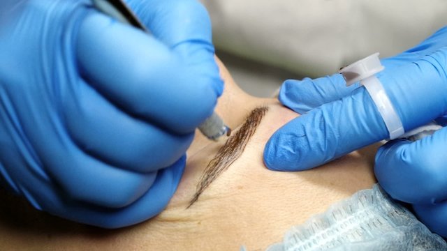 Microblading procedure. Master works with the eyebrows. Semi-permanent make-up.