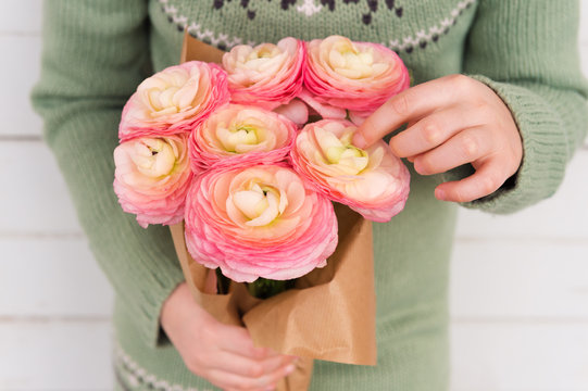 Beautiful bouquet of soft pink ranunculus in child's hands, mother's day concept