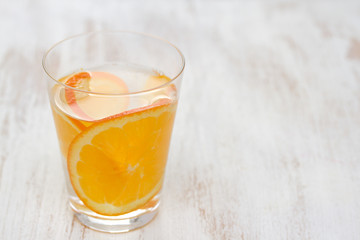 orange drink in glass on white wooden background