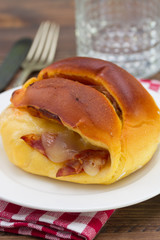 bread with cheese and meat on white plate and glass of water on brown wooden background