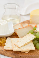 cheese with cookies, grapes and white wine on wooden desk