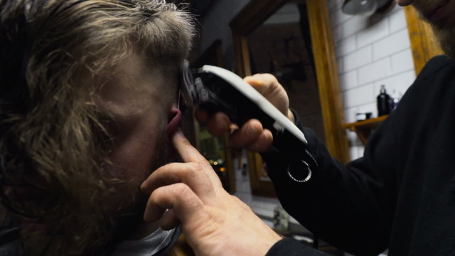 Barber cuts the hair of the client with clipper slow motion close up