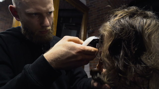 Barber cuts the hair of the client with clipper slow motion