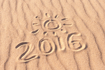 Sign 2016 and sun written on sandy beach. Summer travel concept