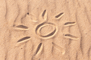 simple sun drawing in the sand on The beach. Summer travel concept