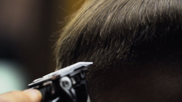 Barber cuts the hair of the client with clipper slow motion close up