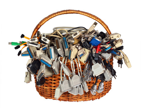 Basket with many different computer interface cables wires connectors sockets and plugs, isolated on white