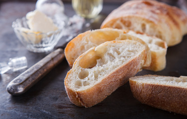 Italian ciabatta bread cut in slices on chopping board with butter,olive oil and salt.selective focus.