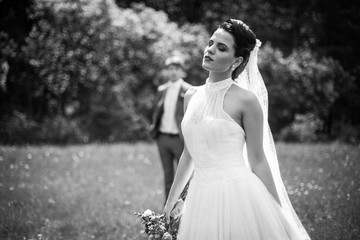 Fototapeta na wymiar Gorgeous brunette bride in elegant dress posing in sunny park b&