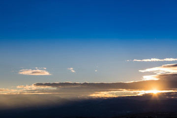 Sunset with orange and blue sky above ground, aerial shot.