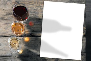 Wein in Gläsern auf Holztisch, mit einem leeren Blatt Papier.