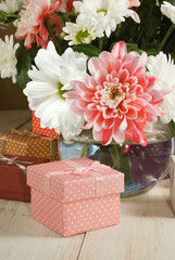 images of flowers and gift box on a wooden table close up