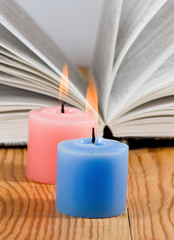 image of two candles on open book background closeup