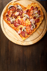 Pizza heart shape on dark wooden background top view