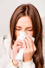 Close up portrait of sick woman  with fever sneezing in tissue