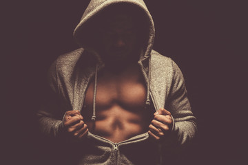 Man with hoodie shows his perfect abdominal muscles