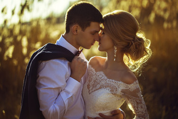 young wedding couple, beautiful bride with groom portrait on the sunset near the ears of wheat,...