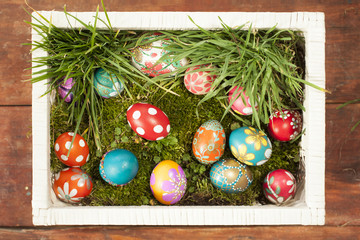 Colorful easter eggs on grass in white basket
