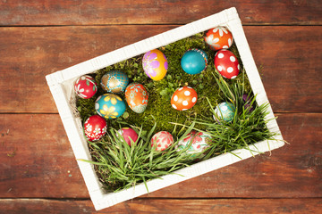 Colorful easter eggs on grass in white basket