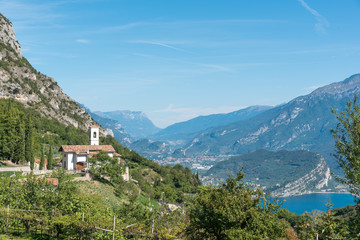 Fototapeta na wymiar St. Georgio Kirche in der Berglandschaft von Pregasina, im Hintergrund der Gardasee und der Berg Brione bei Riva