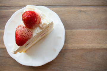 Slice of strawberry shortcake on wooden table with copy space.