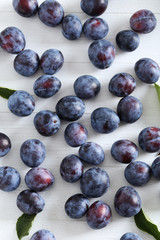 Fresh plums on the white wooden background