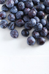 Fresh plums on the white wooden background