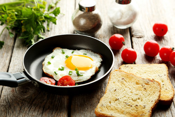 Fried eggs in pan on grey wooden table