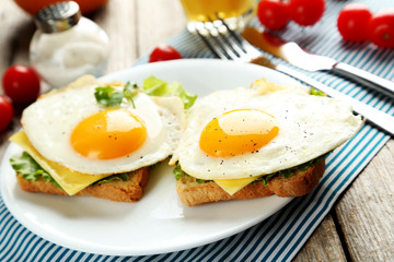 Fried eggs with toasts on plate on grey wooden table