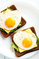 Fried eggs with toasts on plate on blue wooden table