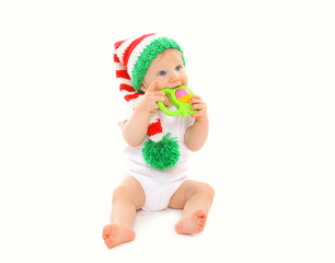 Baby in knitted hat playing with toy on white background