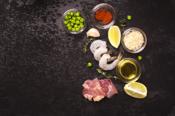 Obraz na płótnie Canvas Spanish paella ingredients over black stone background. Top view. Toned image