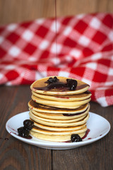 stack of pancakes white plate with cherry jam, red  napkin, brow