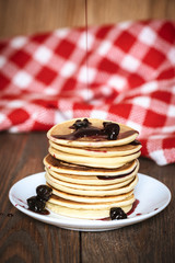 stack of pancakes white plate with cherry jam, red  napkin, brow