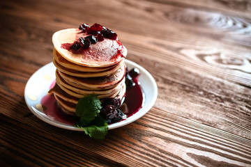 stack of pancakes on a white plate with cherry jam, mint leaves,