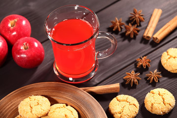 Composition with a large cup of hot drink, which stands on a rustic vintage black table next to a plate of homemade cookies, red apples, star anise and cinnamon sticks. Selective focus