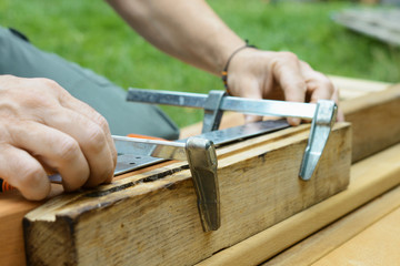 Schreiner oder Handwerker fixiert Holzbalken mit Schraubzwinge